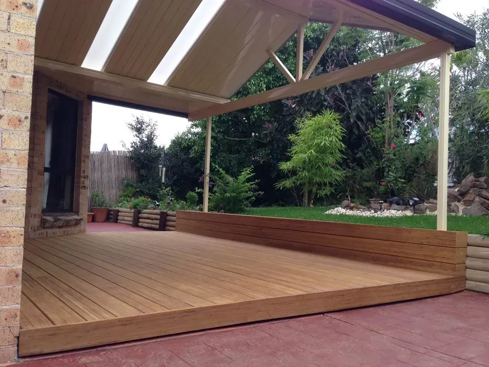 Wooden deck with a roofed patio area, overlooking a grassy backyard.