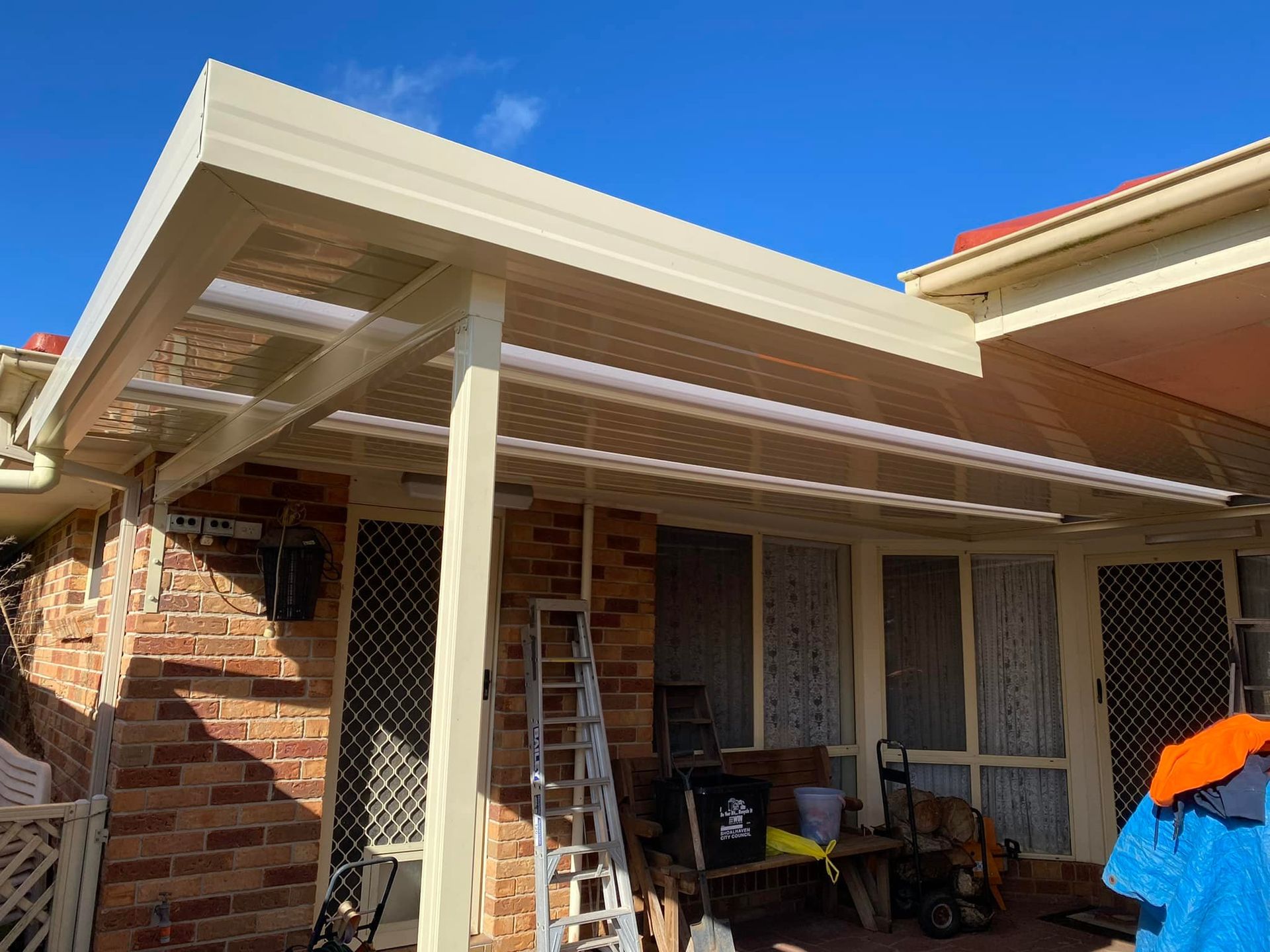 Beige patio cover attached to a brick house, with clear roof panels.