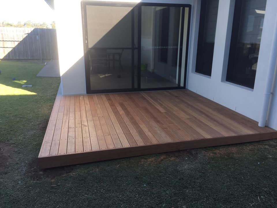 A wooden deck in front of a house with sliding glass doors