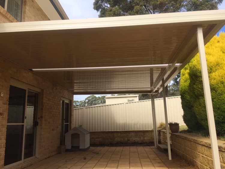 A patio with a canopy over it and a dog house in the background.
