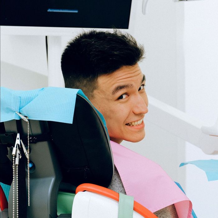 a man is smiling while sitting in a dental chair