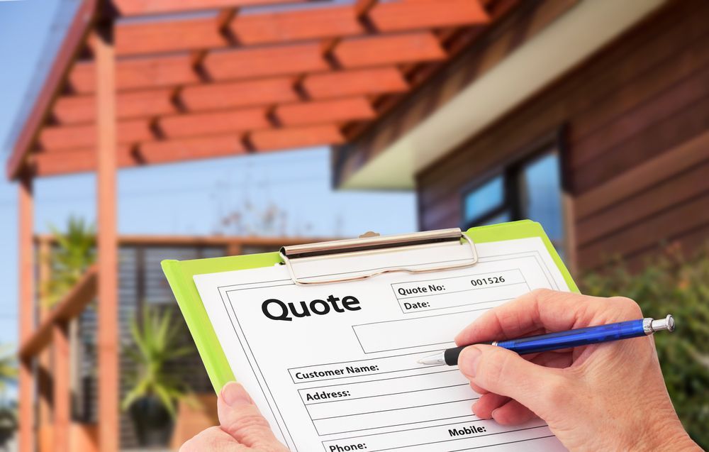 A Person is Holding a Clipboard With a Quote on It in Front of a House — Rauseo Group in Zuccoli, NT