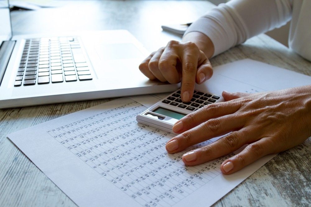 A Person Is Using a Calculator in Front of A Laptop — Rauseo Group in Darwin, NT
