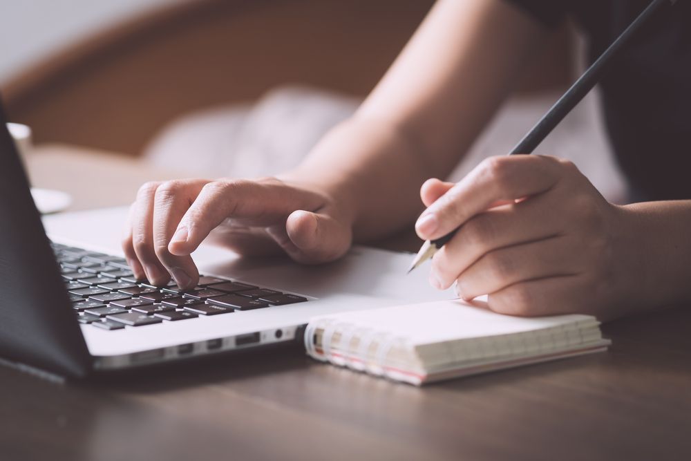 Hands Typing on A Laptop Beside a Notebook — Rauseo Group in Darwin, NT