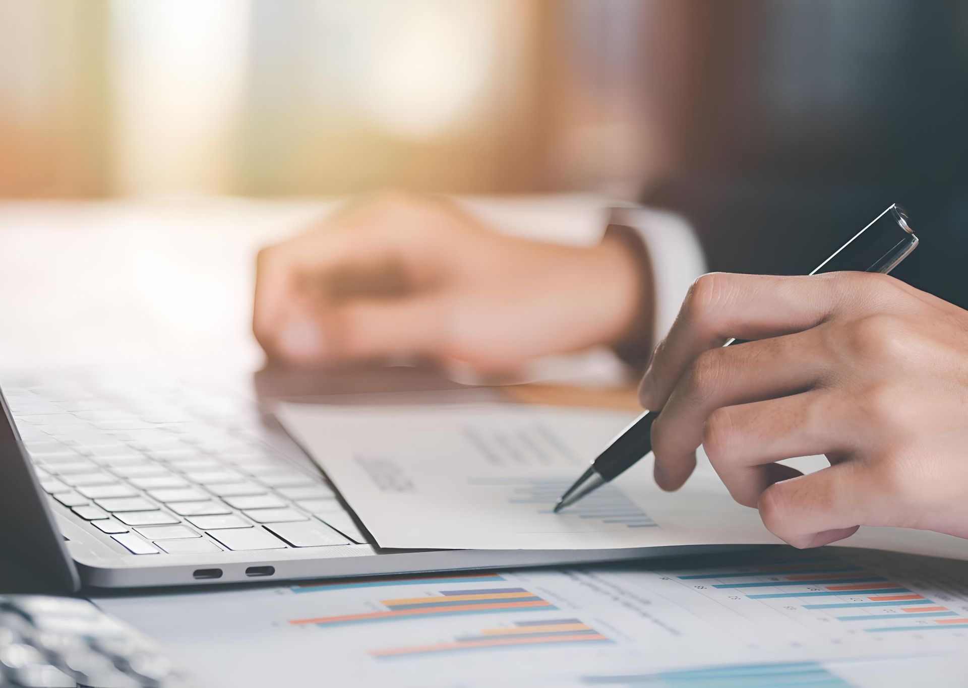 Hands Writing on A Notebook Beside a Laptop on A Desk with Charts — Rauseo Group in Darwin, NT