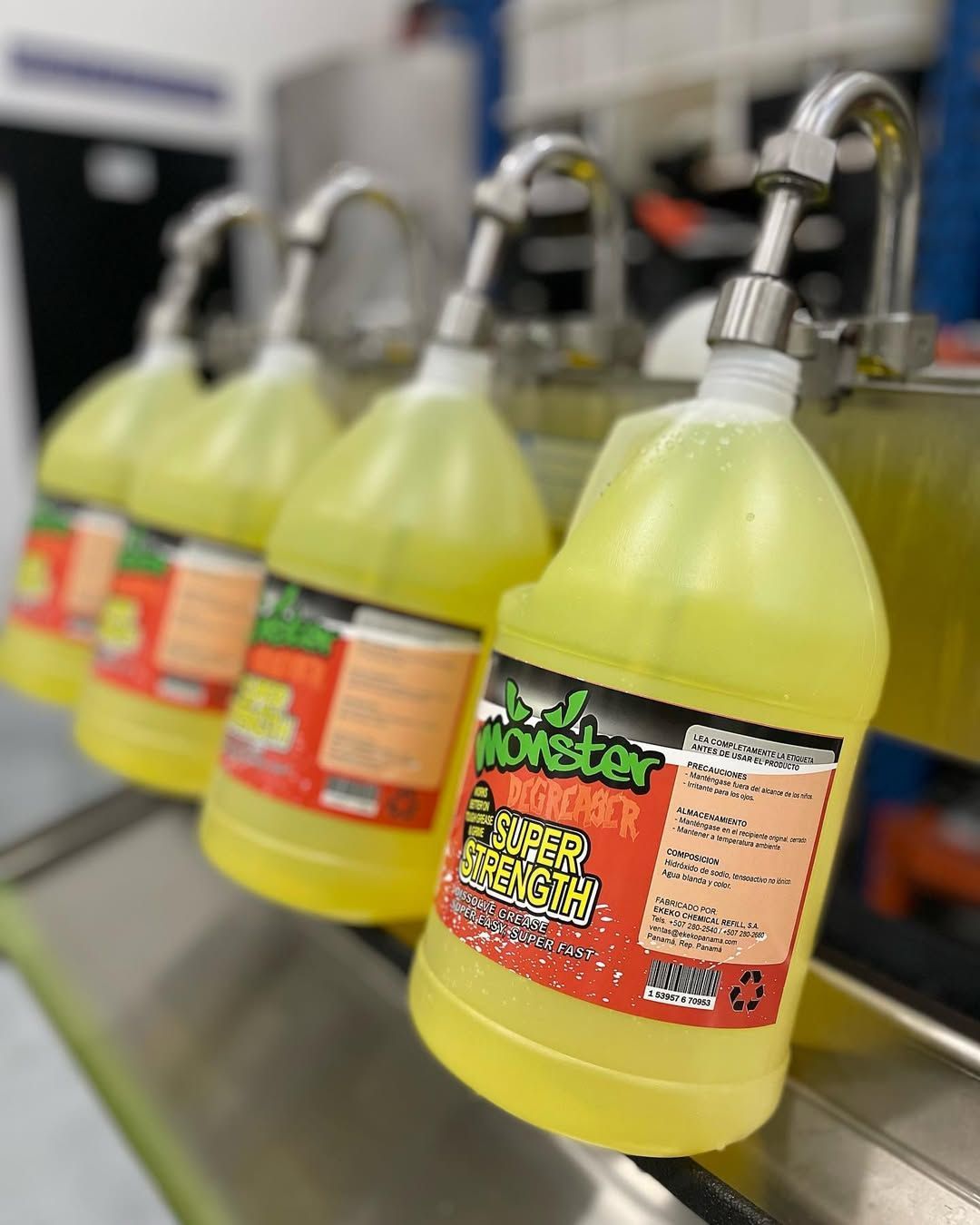 Filas de botellas amarillas con pulverizadores metálicos en una línea de producción.