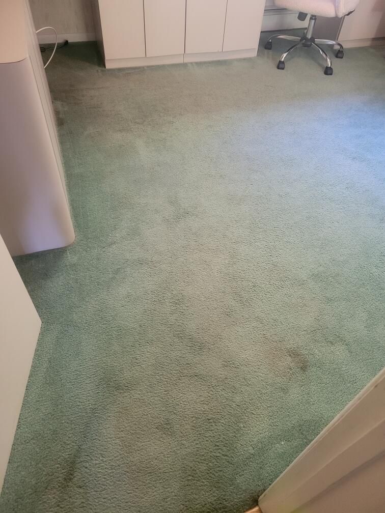 A green carpeted floor in a room with a desk and chair.