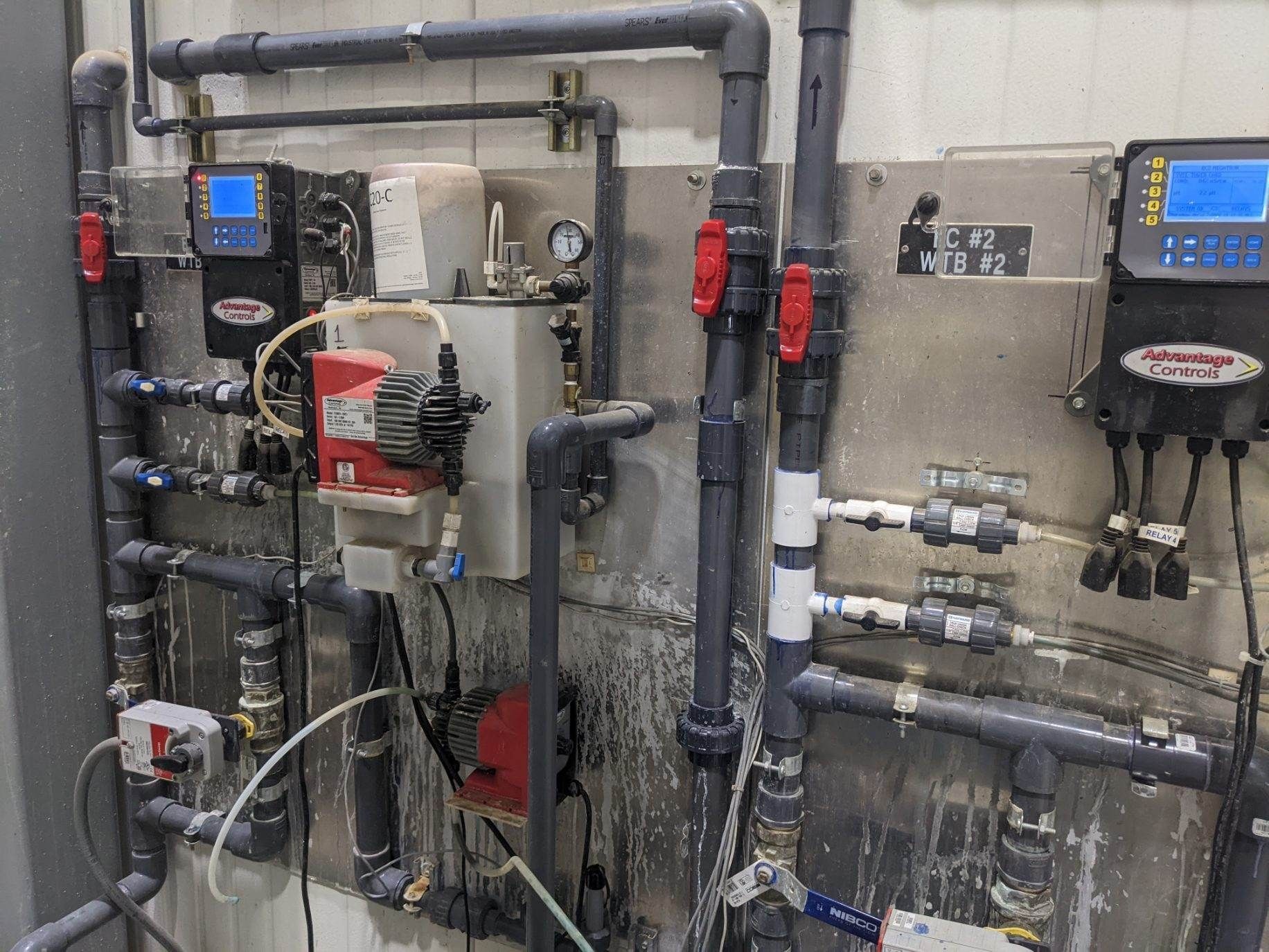 Industrial piping and control panels on a wall in a mechanical room