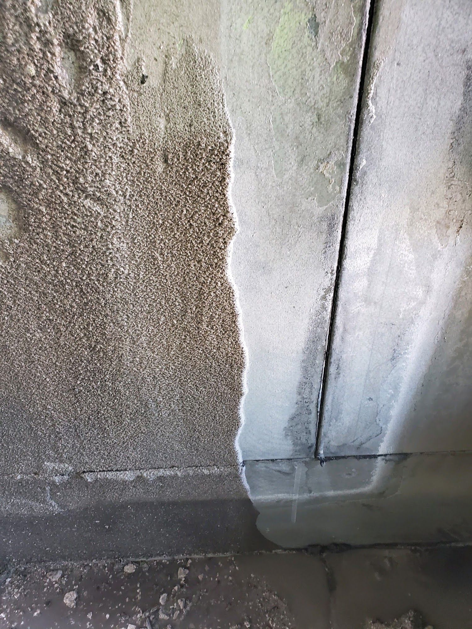Weathered concrete wall with water damage, peeling paint, and a damp stained corner.