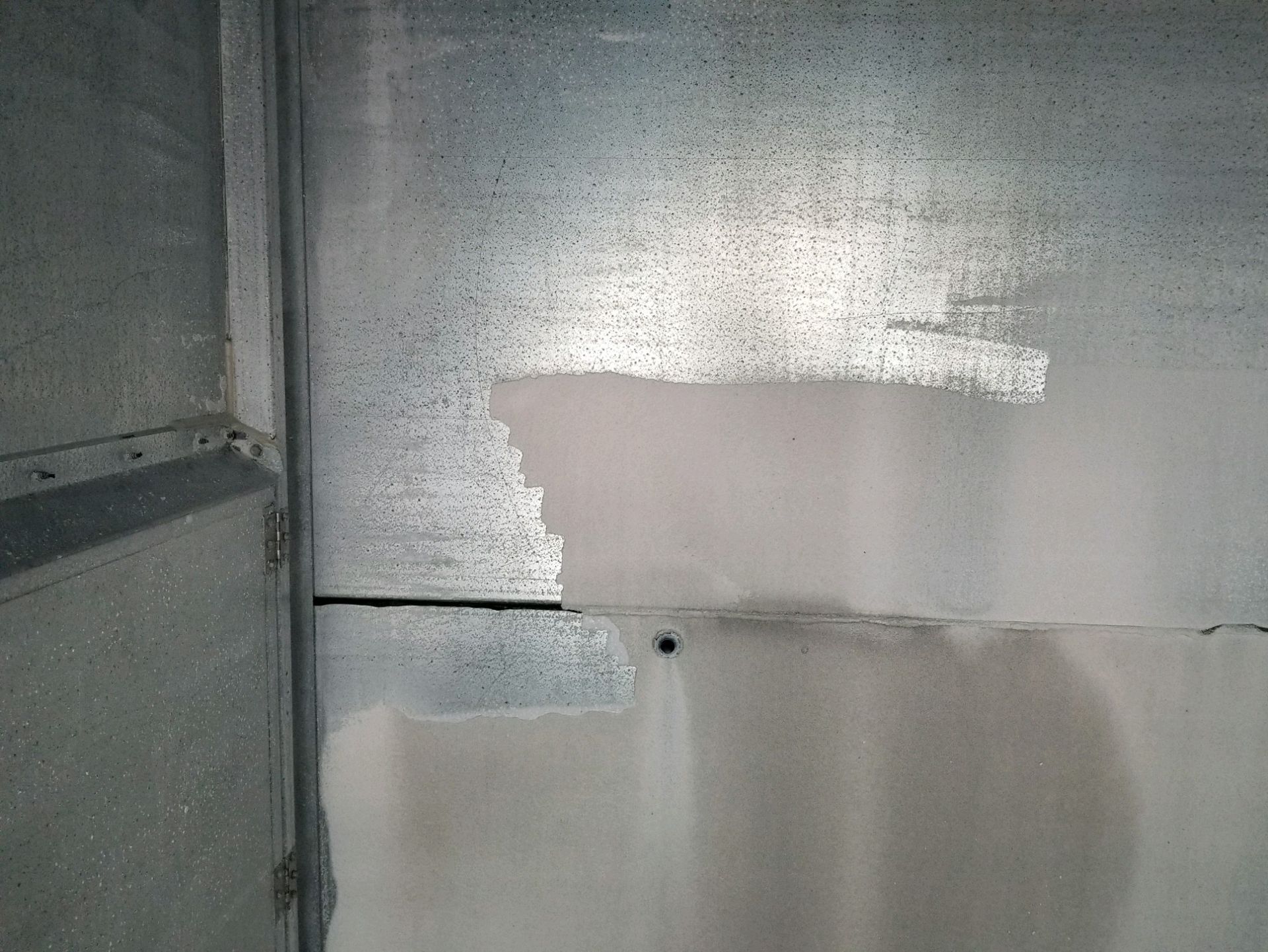 Patchy drywall repair inside a gray metal or unfinished wall corner