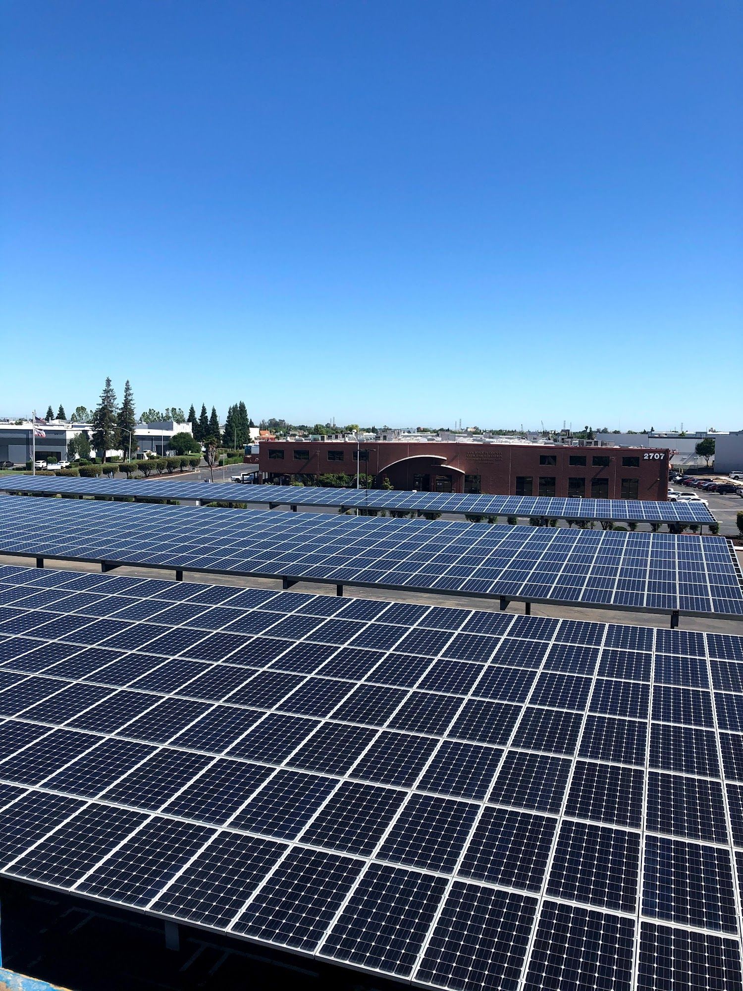 Rows of solar panels on a rooftop under a clear blue sky
