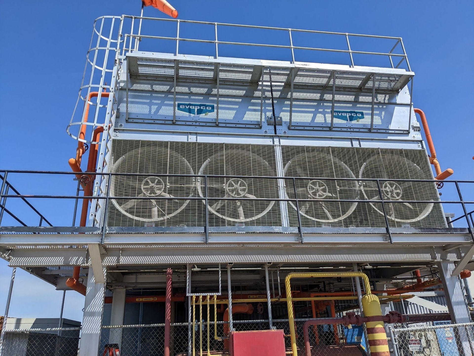 Industrial building with large cooling fans, metal scaffolding, and a blue sky overhead