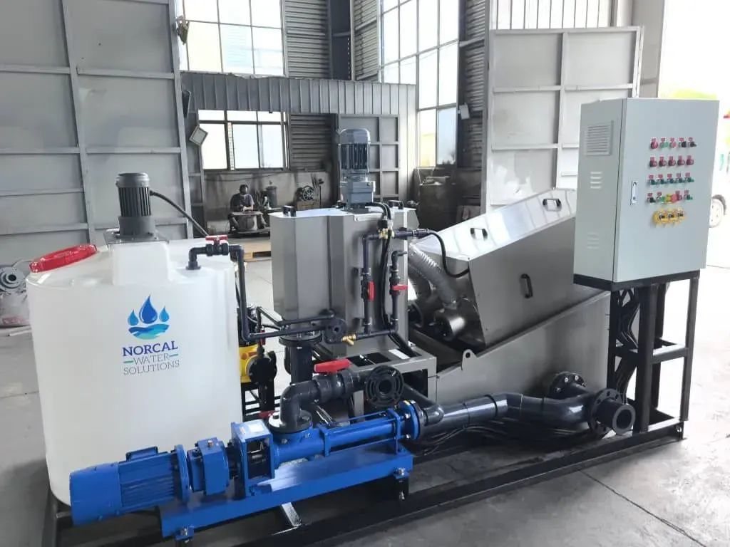 Industrial machine with blue motor and white control tanks in a factory workshop