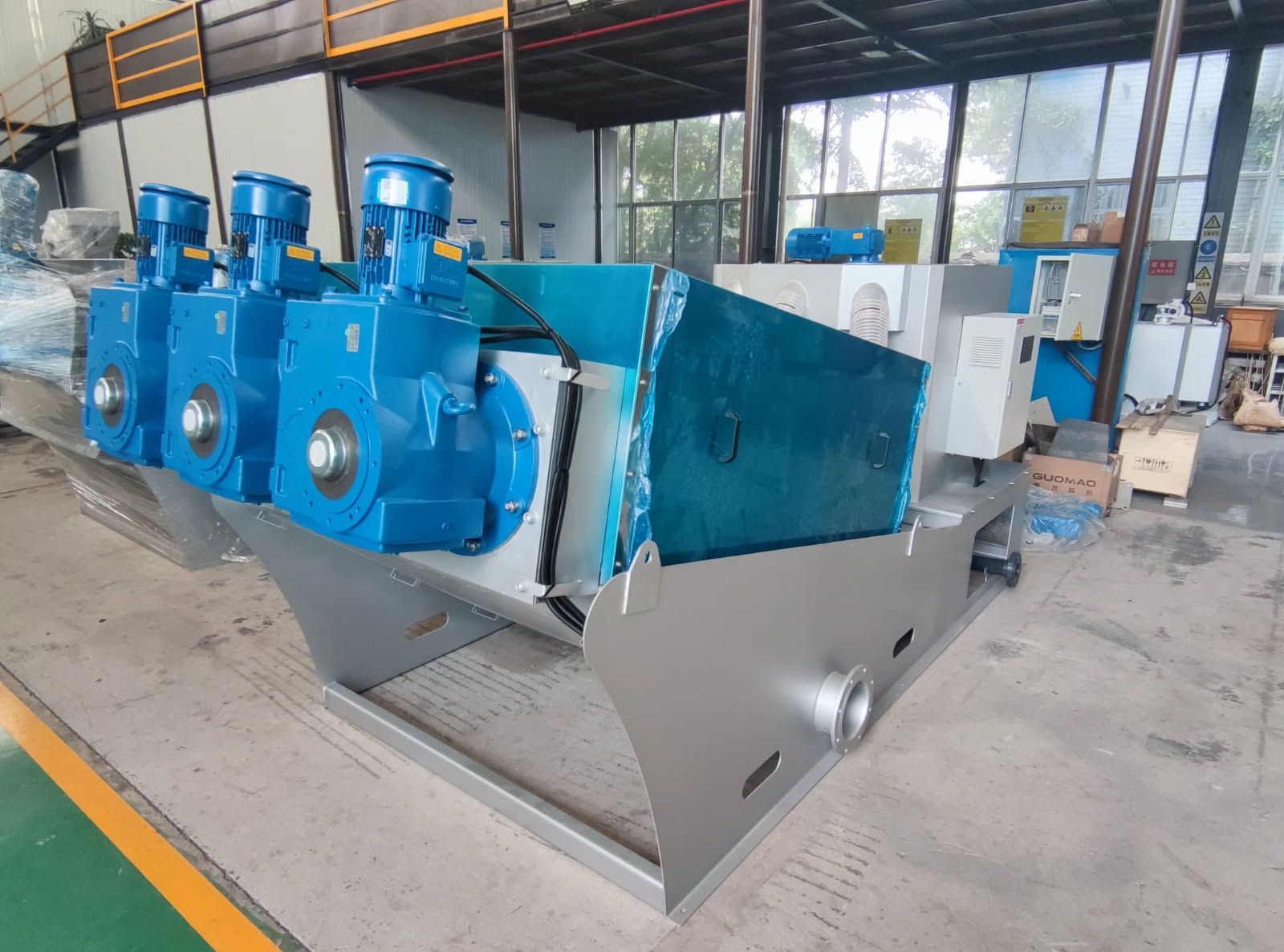 Blue industrial machinery in a factory workshop, mounted on a silver base