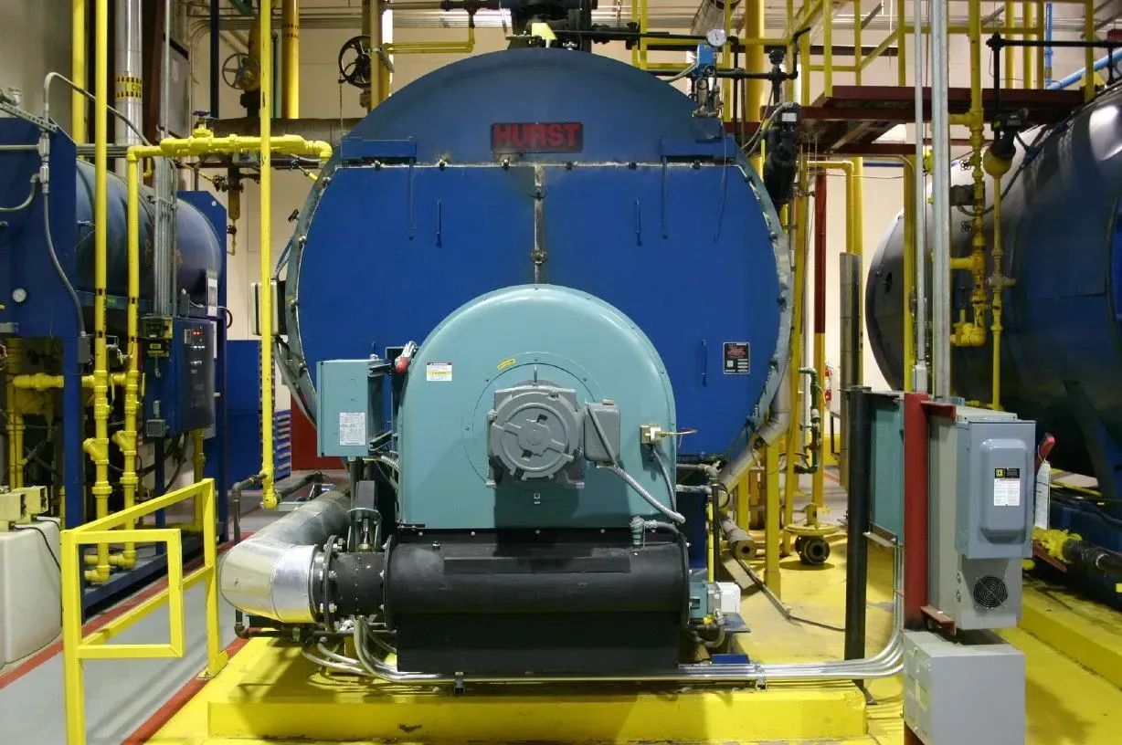 Industrial machinery in a factory, with large blue tanks and yellow piping.