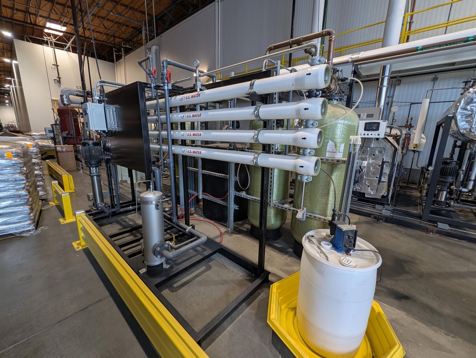 Industrial machinery with white cylindrical filters and pipes in a factory workshop