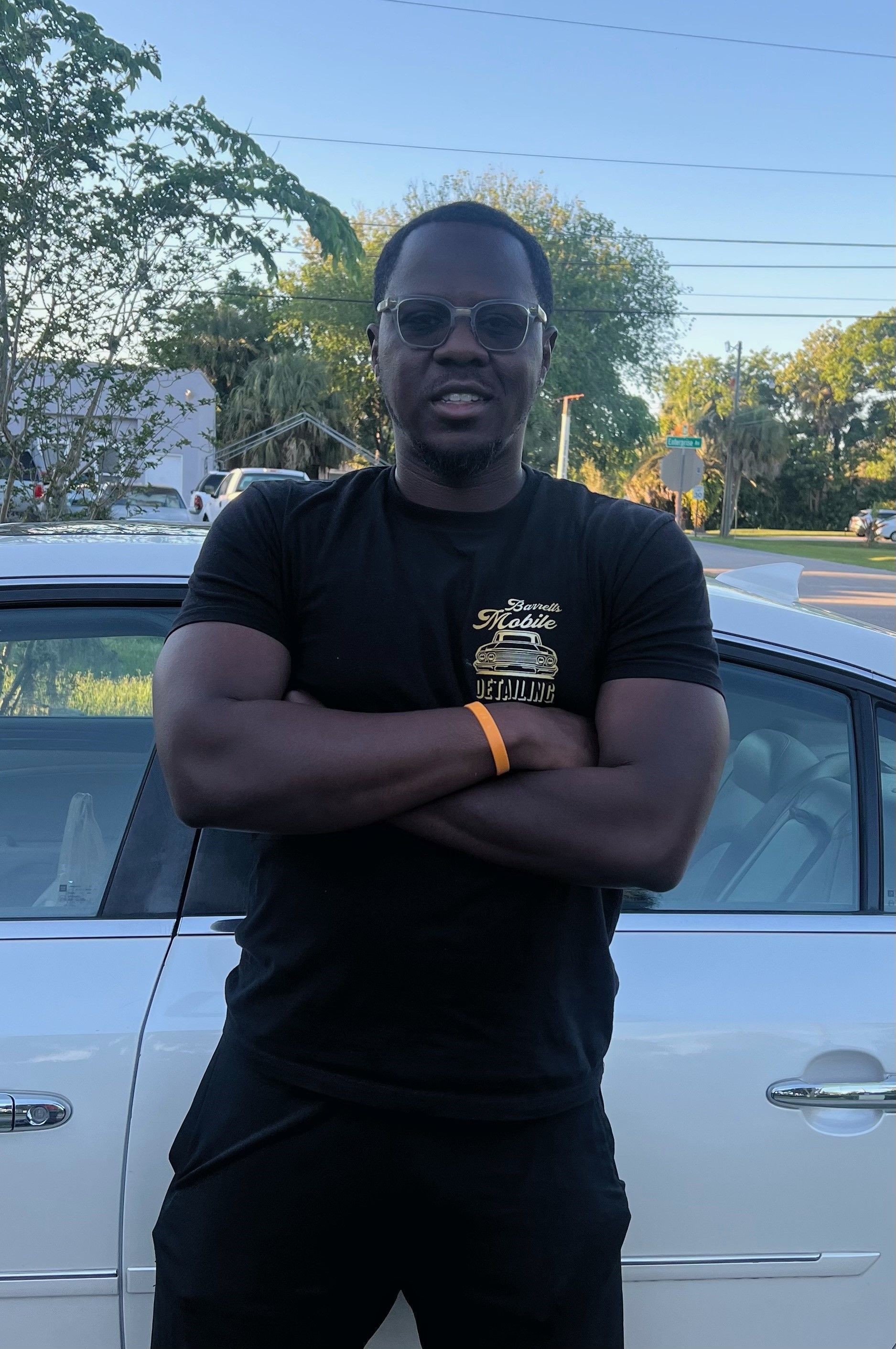 A Man is Standing in Front of a White Car With His Arms Crossed