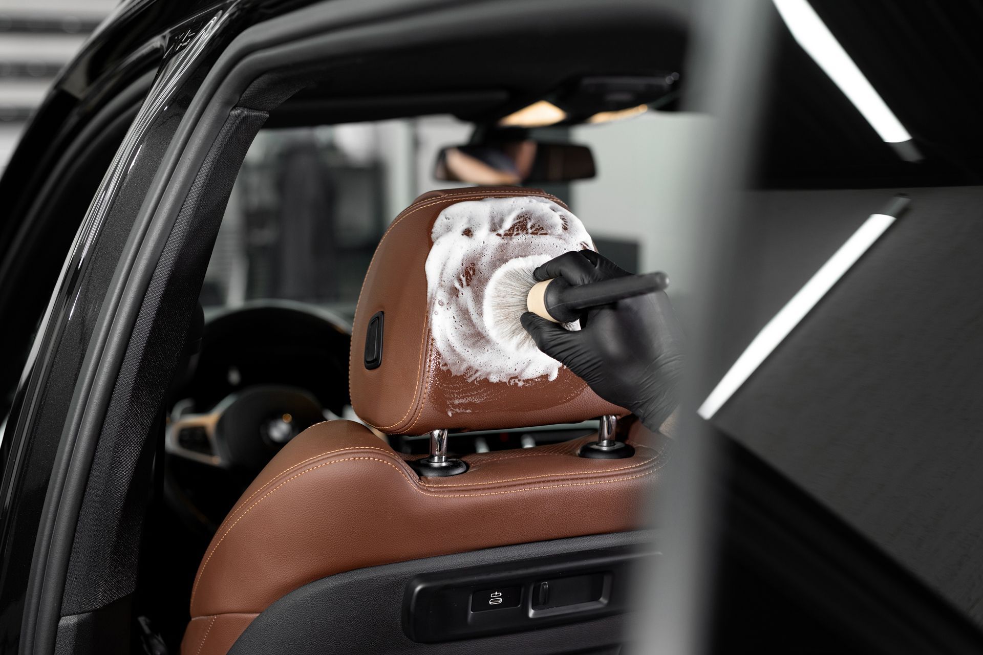 A Person is Cleaning the Headrest of a Car With a Brush