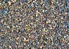 Close-up of multicolored gravel stones, mostly gray, tan, and purple.
