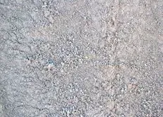 Close-up of gray gravel or rough concrete surface with small stones and speckled texture