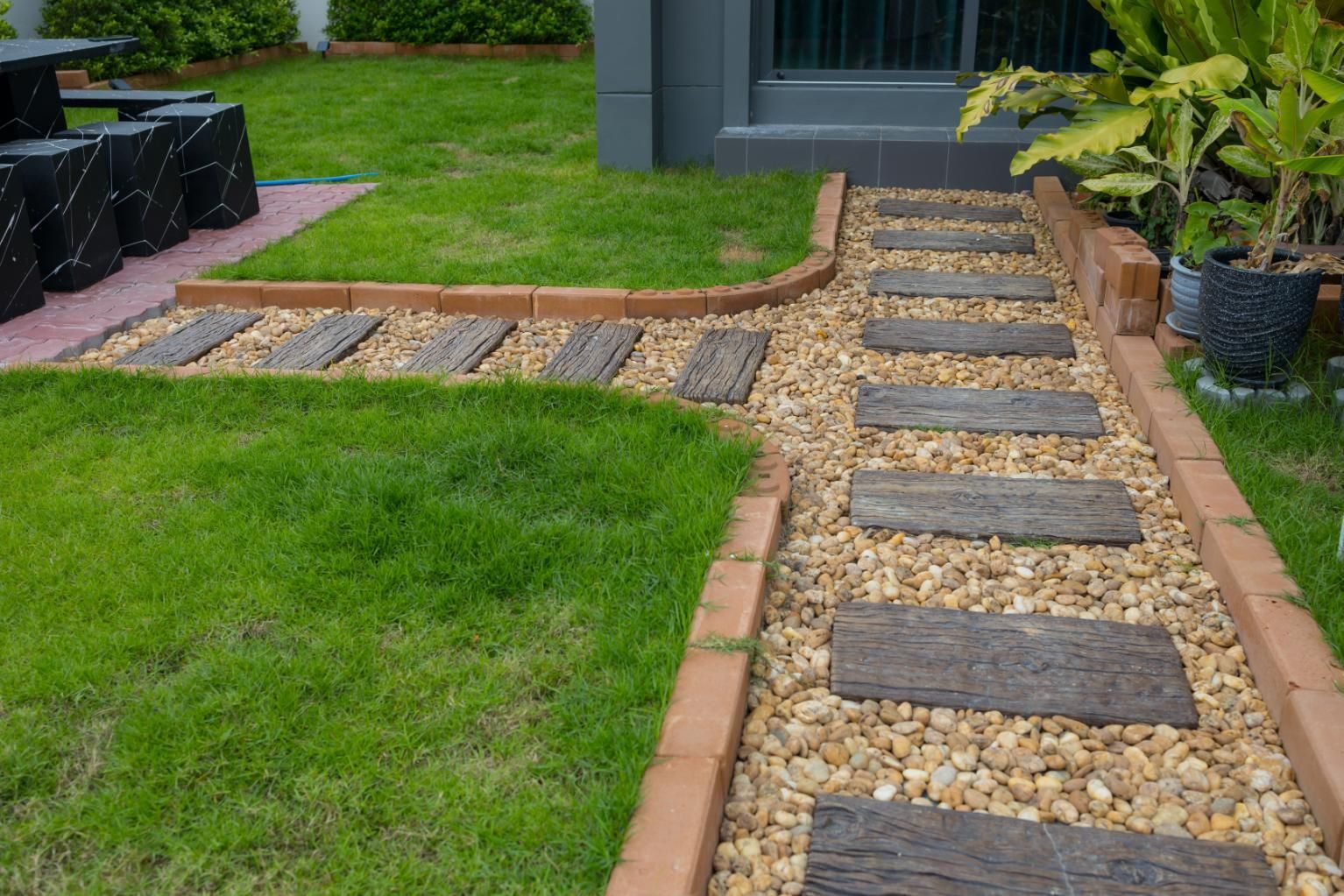 Front yard stone path with gravel and brick borders leading to a house entrance
