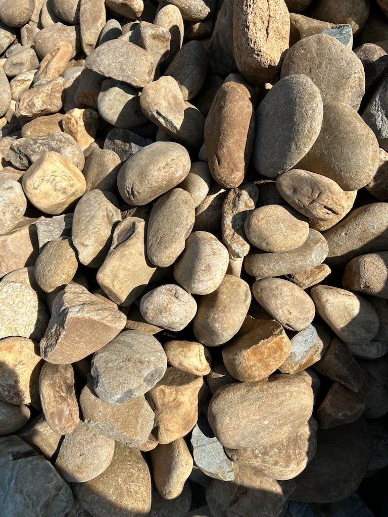 Pile of smooth tan and gray pebbles and small rocks outdoors