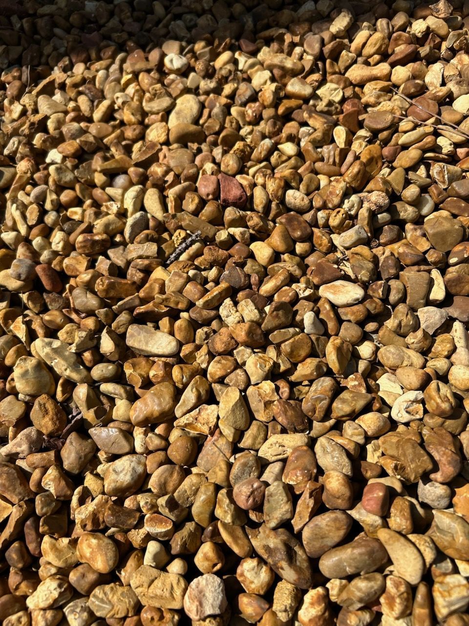 Close-up of a pile of small brown pebbles and stones covering the frame