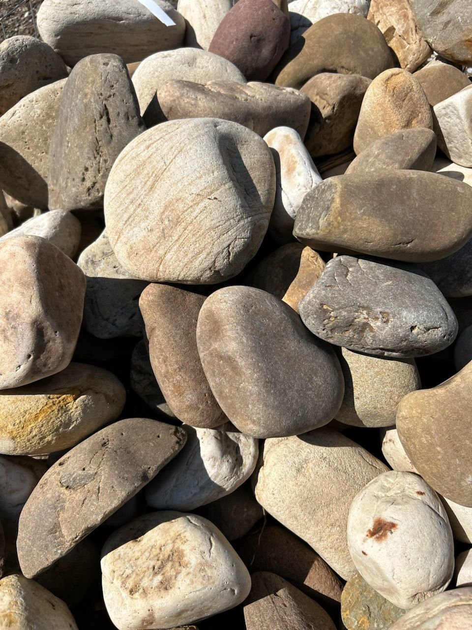 Close-up of smooth beige and gray river rocks piled together