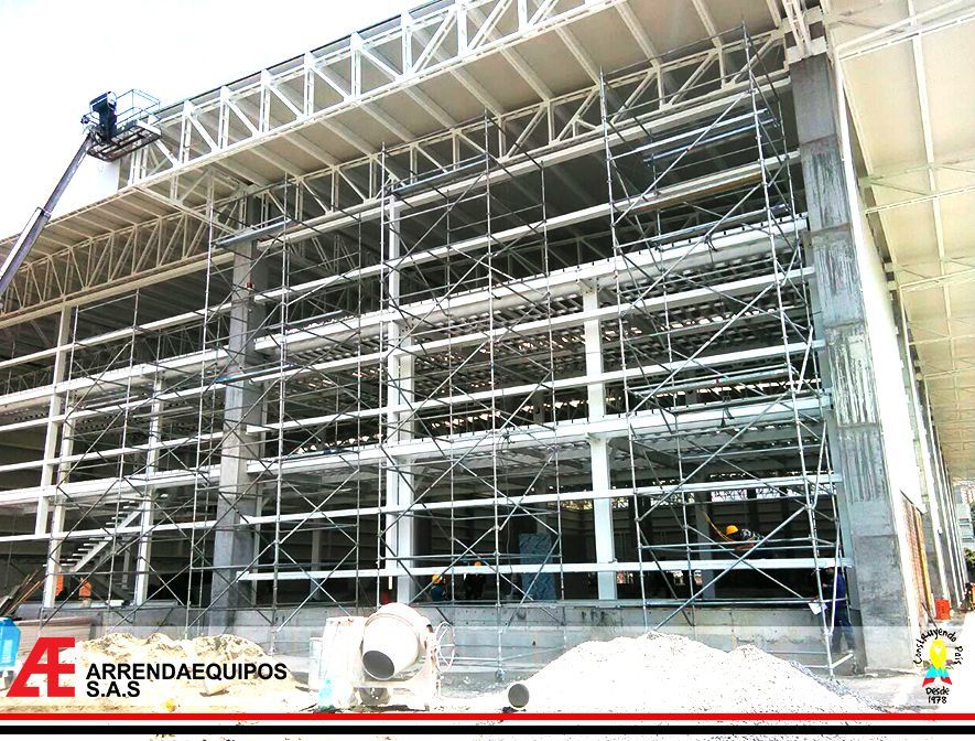 Obra con andamios. Se ven trabajadores, una grúa y una estructura parcialmente construida.