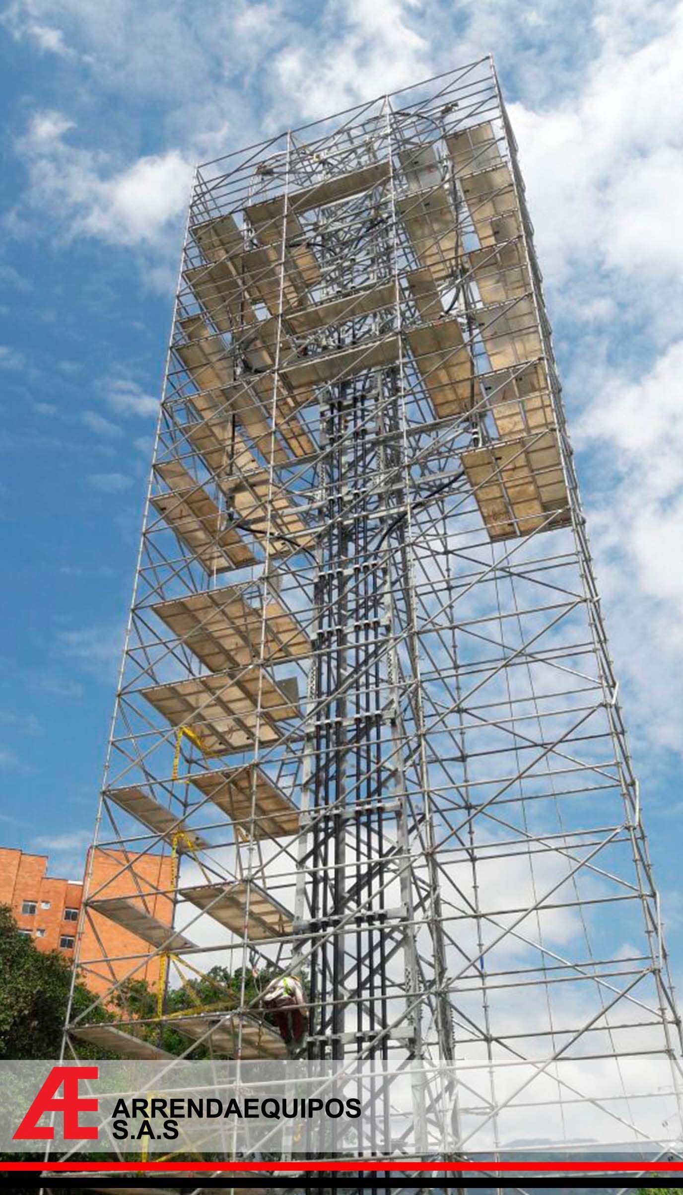 Estructura alta de andamios metálicos contra un cielo azul, con plataformas de madera para los trabajadores.