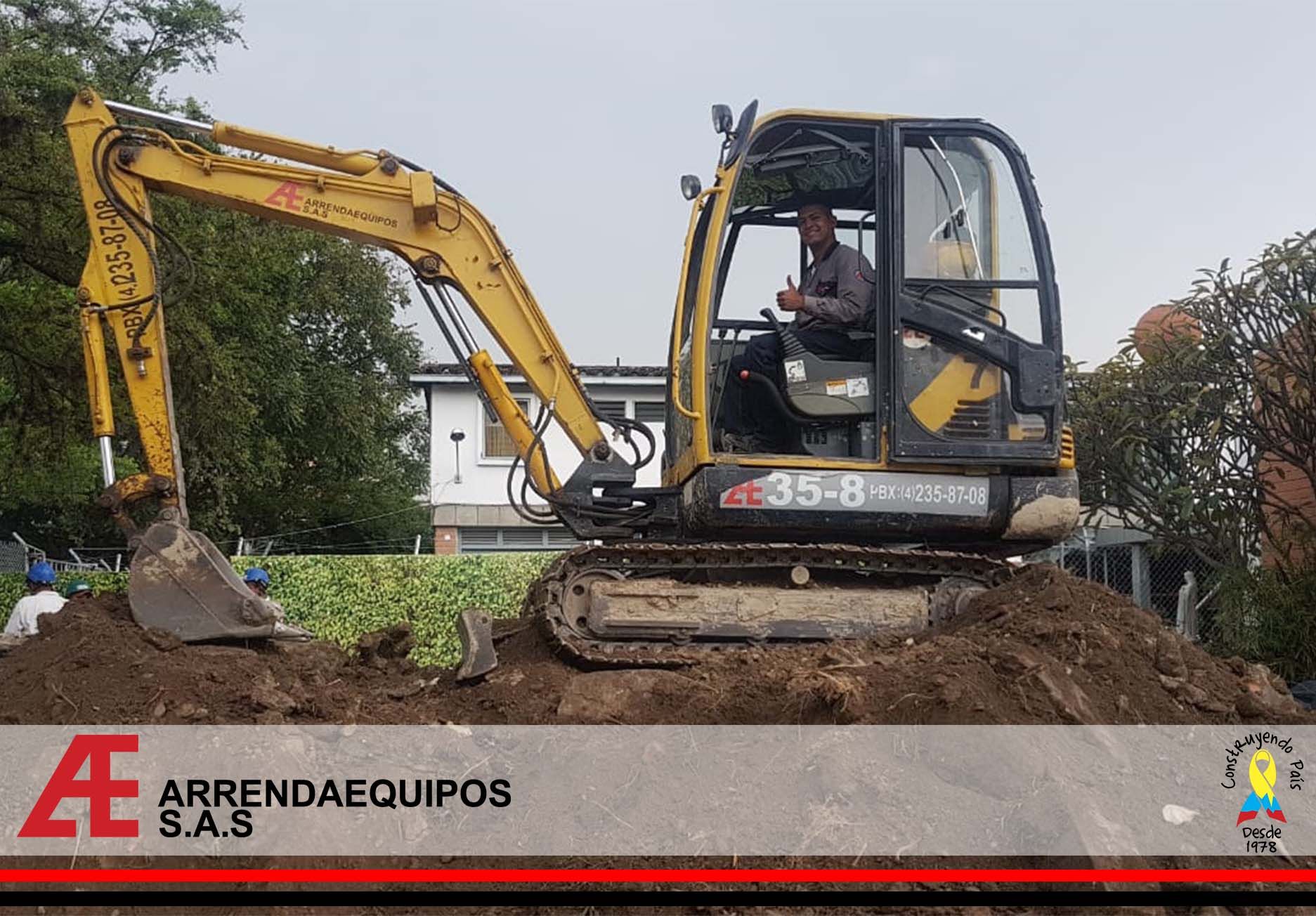 Excavadora amarilla con una persona en la cabina excavando tierra. Logotipo de 