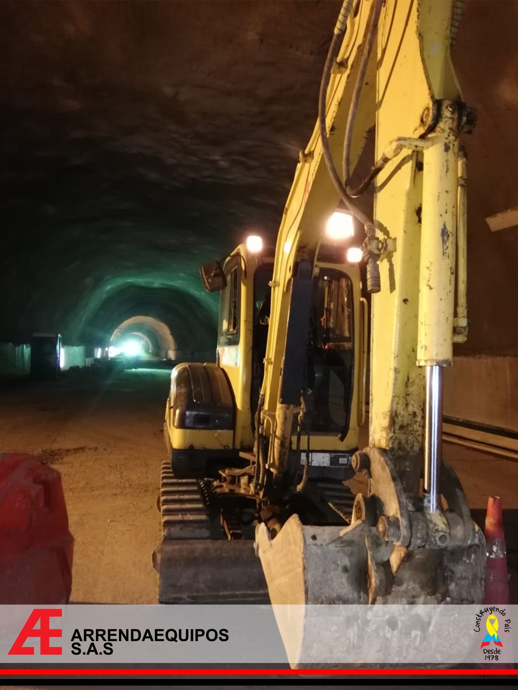 Excavadora amarilla dentro de un túnel; las luces iluminan el oscuro interior.