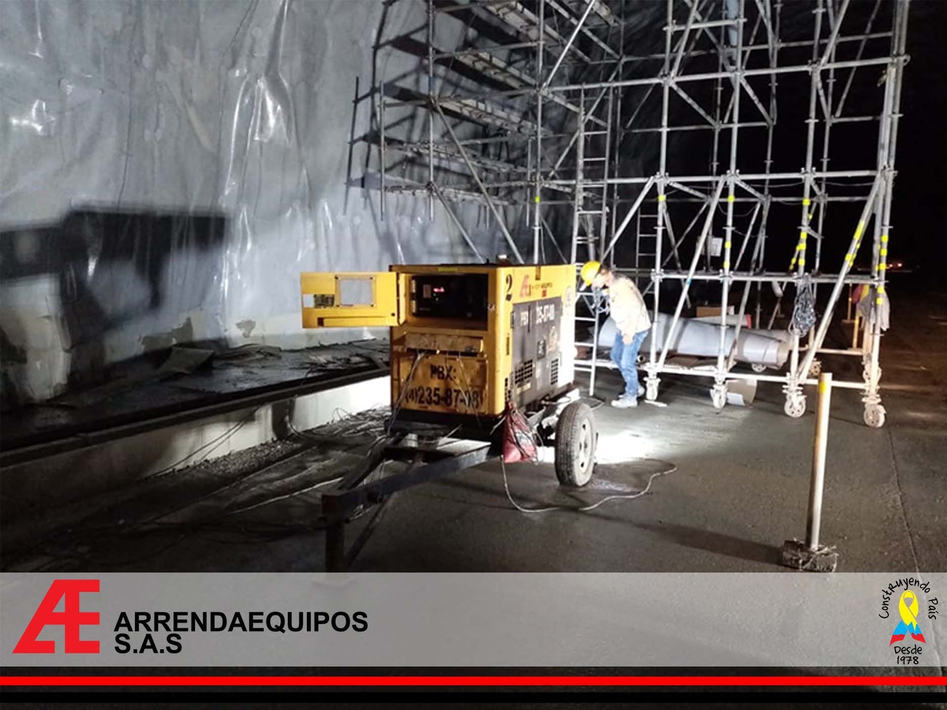 Un generador amarillo en un sitio de construcción al lado de un andamio; una persona está trabajando.