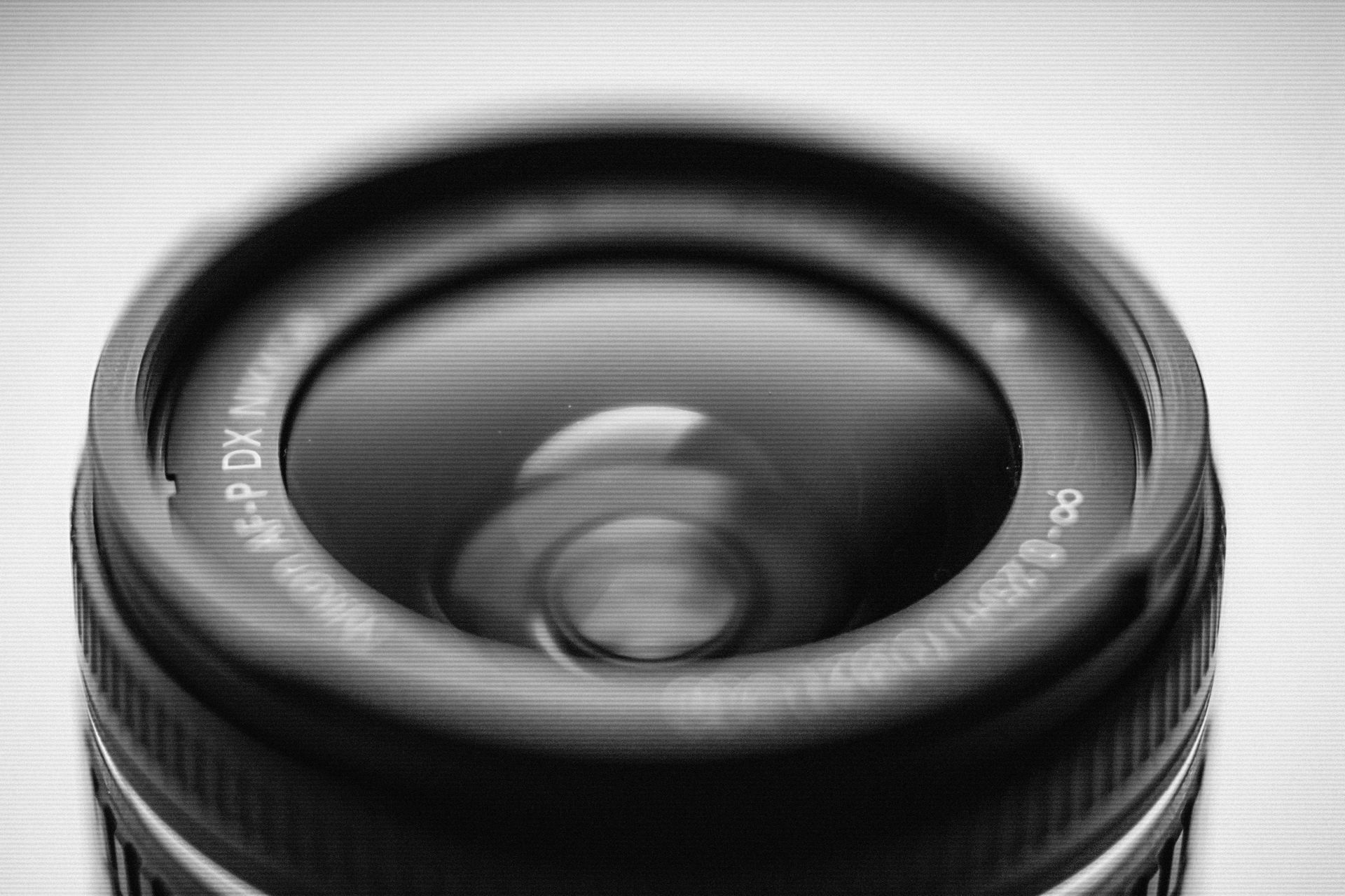 Close-up van een cameralens met een reflecterend glazen oppervlak en witte markeringen op de rand.