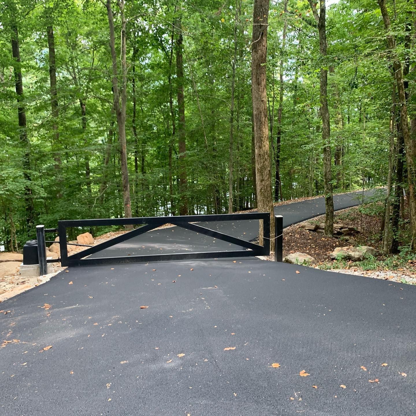 A black gate on the side of a road in the woods