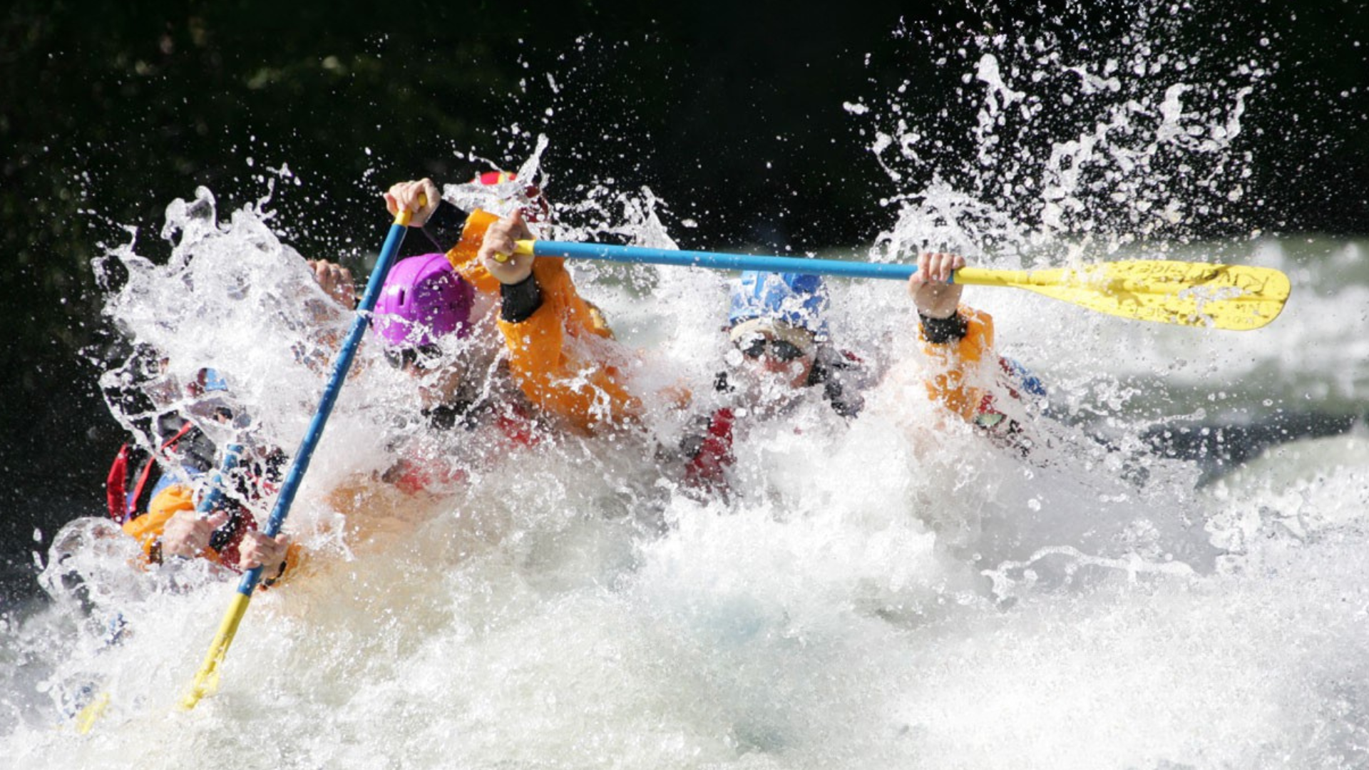 A man in a red helmet is paddling a white kayak