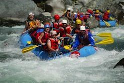 A group of people are rafting down a river in a raft that says jeep on it