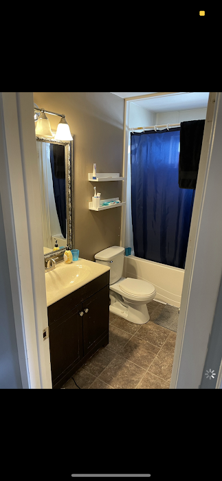 Bathroom with dark brown vanity, white toilet, blue shower curtain, and patterned tile floor.