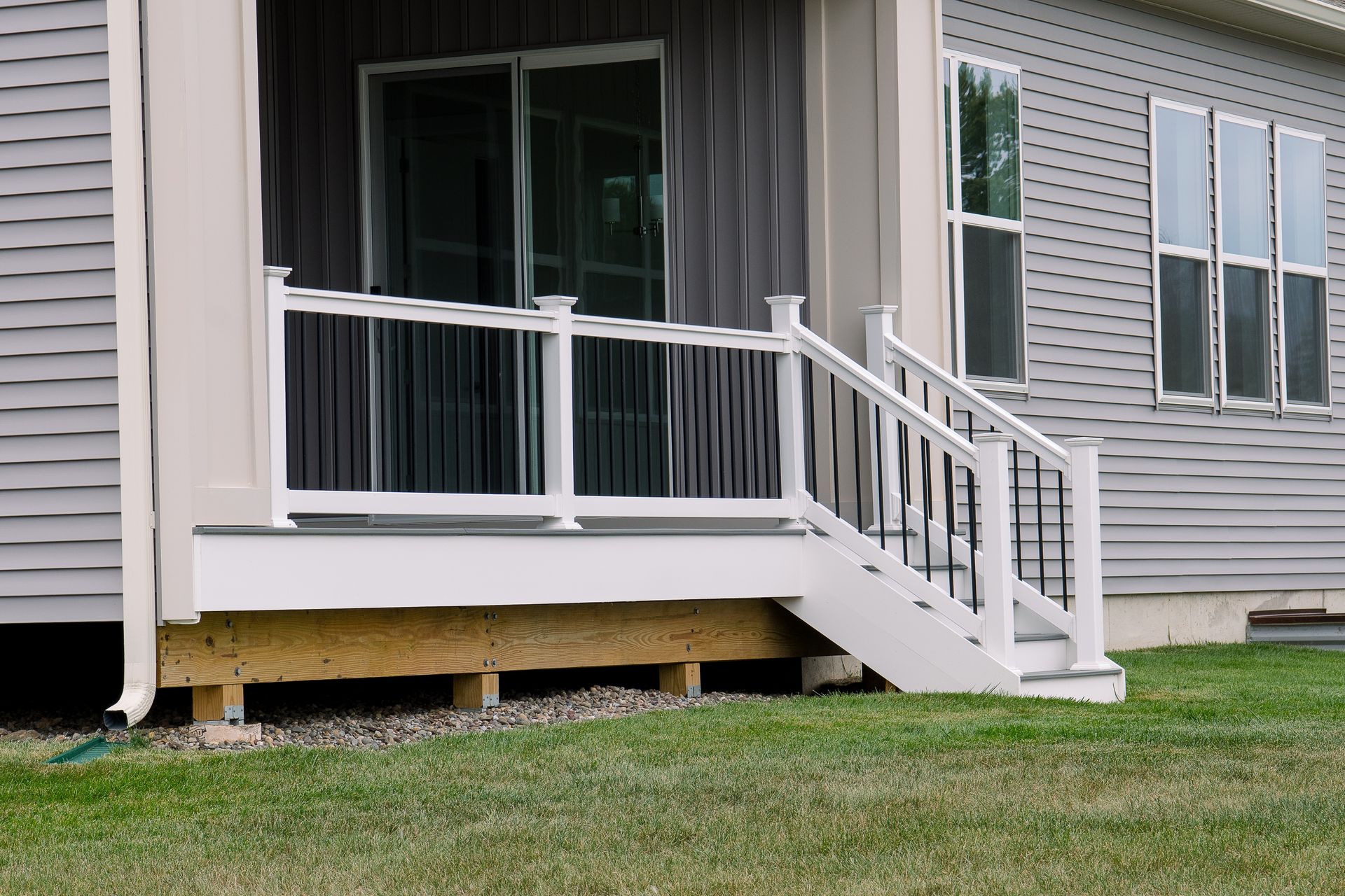 Porch with white railing and stairs on a gray house exterior