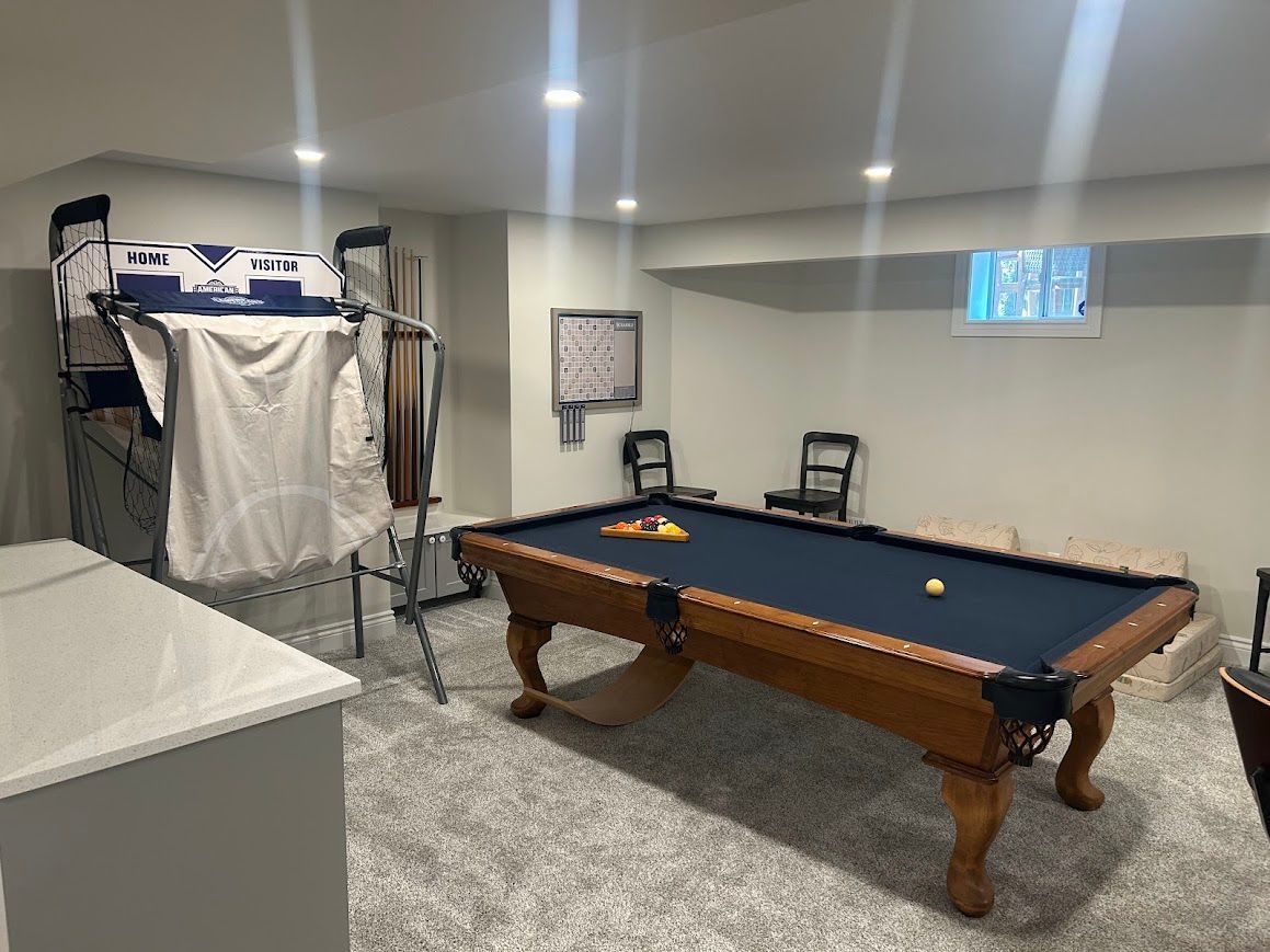 Basement room with a pool table, exercise equipment, and a small window.