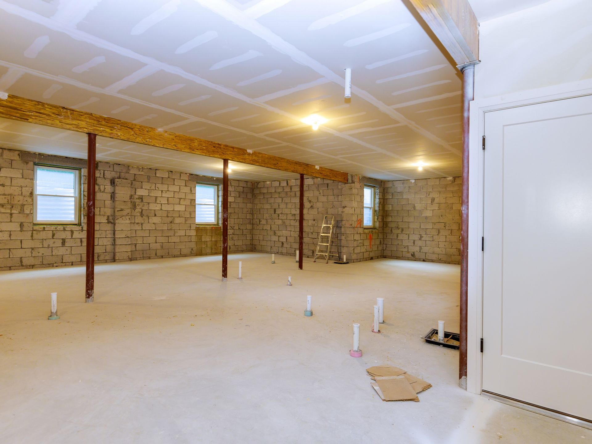 Unfinished basement interior with exposed brick walls, ceiling insulation, and bare concrete floor
