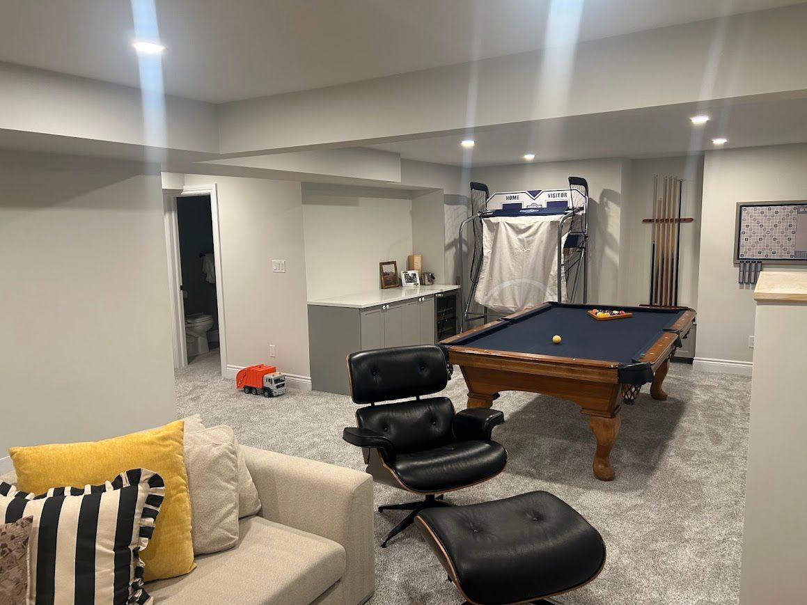 Basement rec room with pool table, recliner, beige sofa, and patterned carpet.