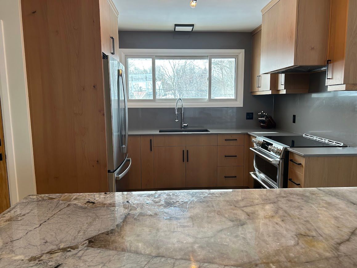 Kitchen with light wood cabinets, stainless steel appliances, and gray countertop.