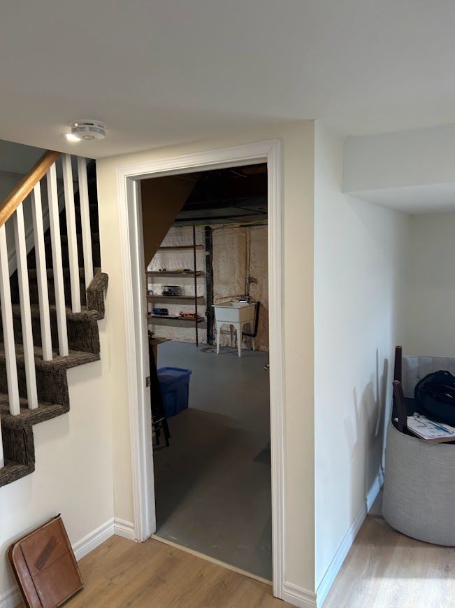 Doorway to a room with shelving and a staircase on the left, neutral walls and flooring.