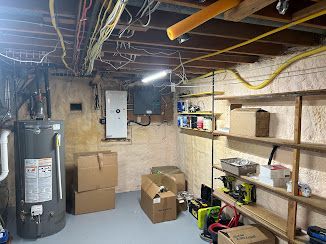 Basement with water heater, storage shelves, electrical wiring, and cardboard boxes.