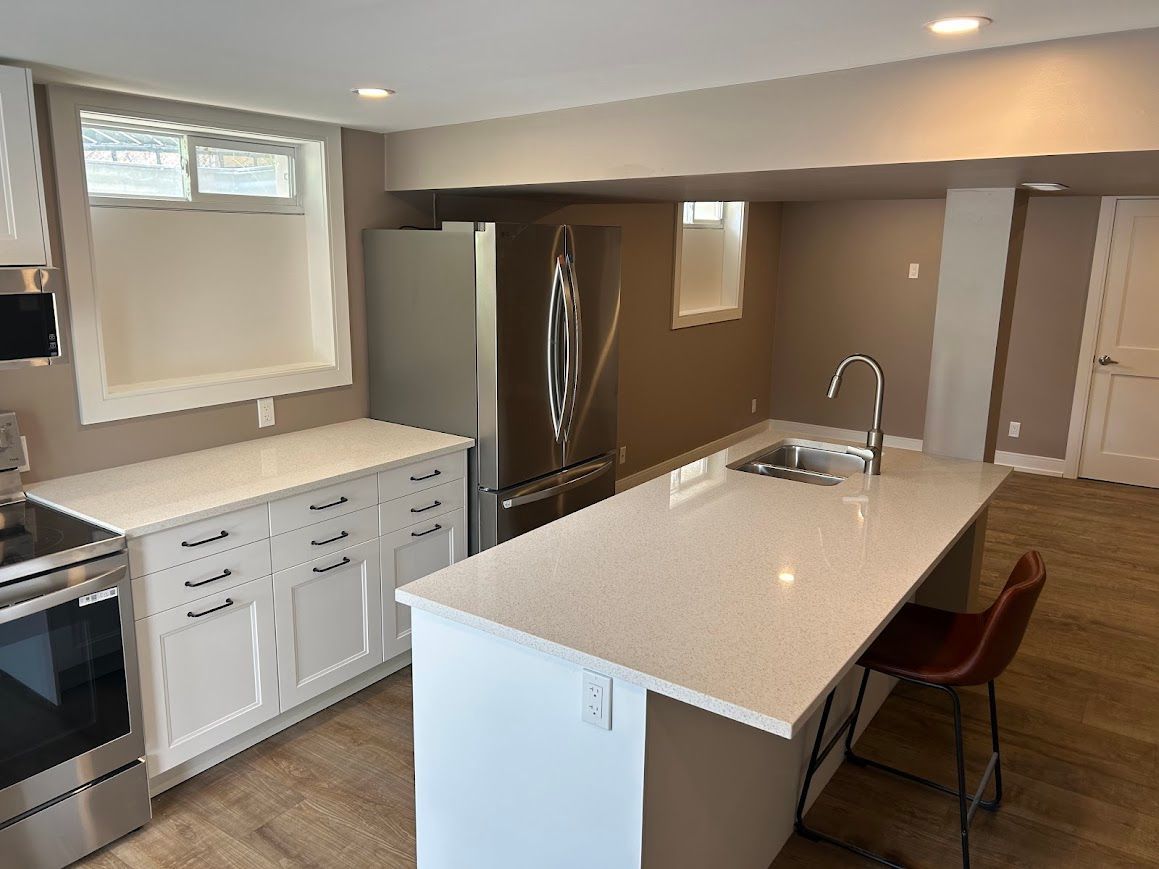 Modern kitchen with white cabinets, stainless steel appliances, and a quartz countertop island.