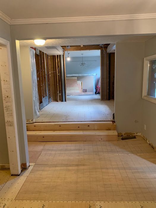 Room under construction with exposed walls and wooden platform. Light wood flooring.