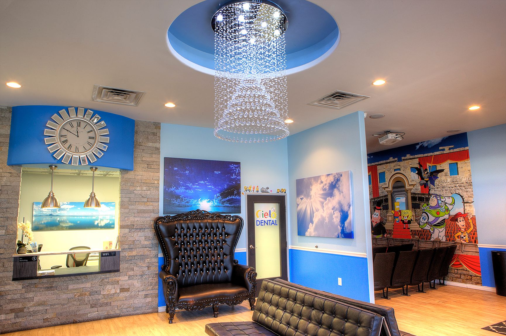 Modern lounge with blue walls, sparkling chandelier, black chair, and colorful wall art
