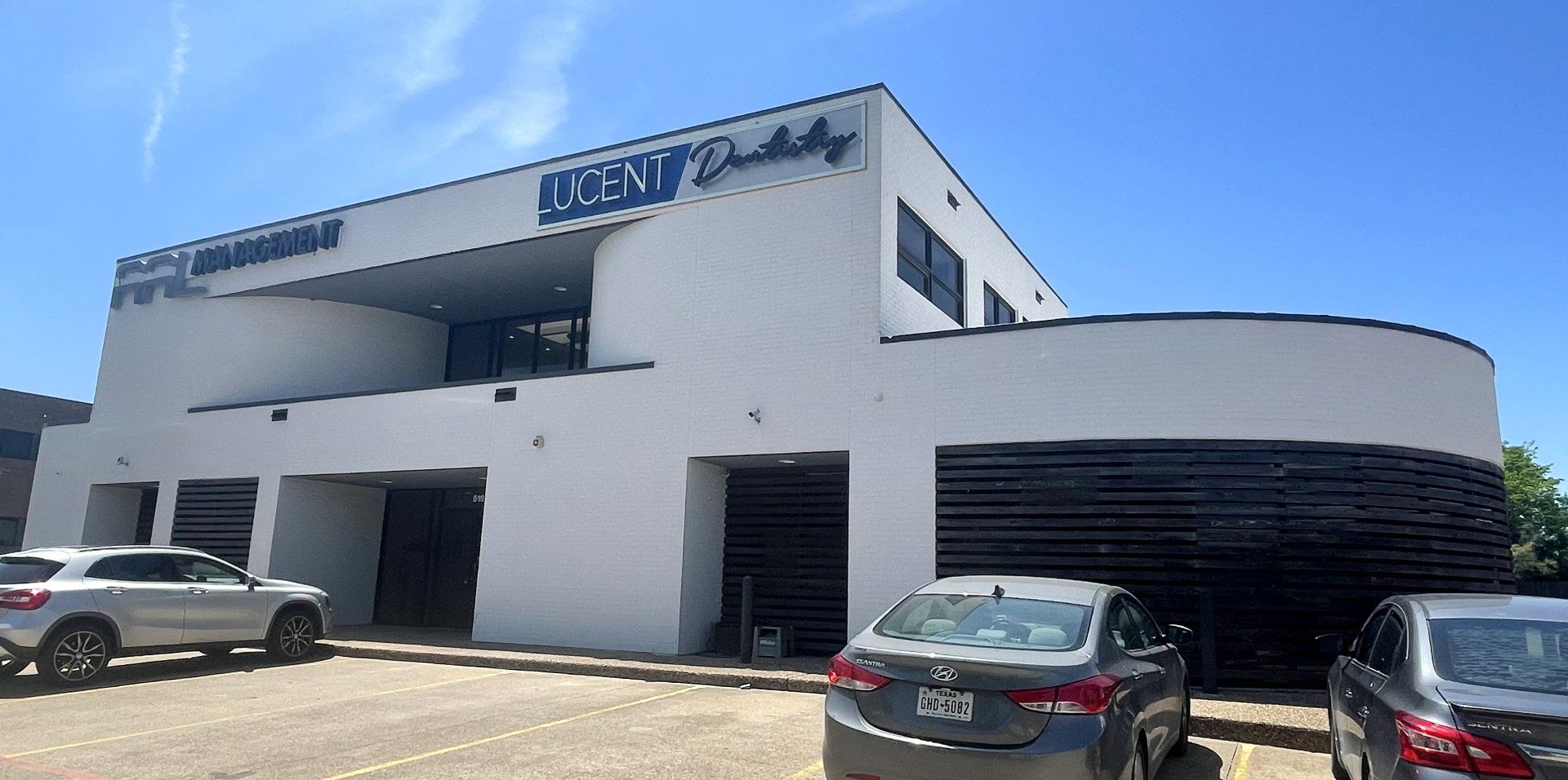 White commercial building with parked cars under a clear blue sky