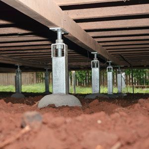 Under-deck jack supports lifting beams above a dirt crawlspace